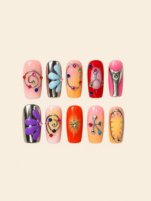 Ten glossy square press-on nails with pink-to-orange gradients, silver swirls, raised blue and purple flowers, starbursts, and colorful gems