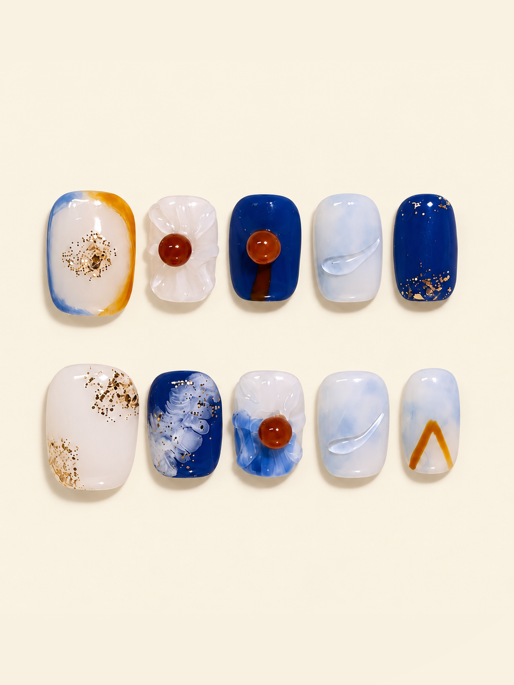 OVANA cobalt blue and white press-on nails with sculpted white flowers, amber centers, and gold flecks