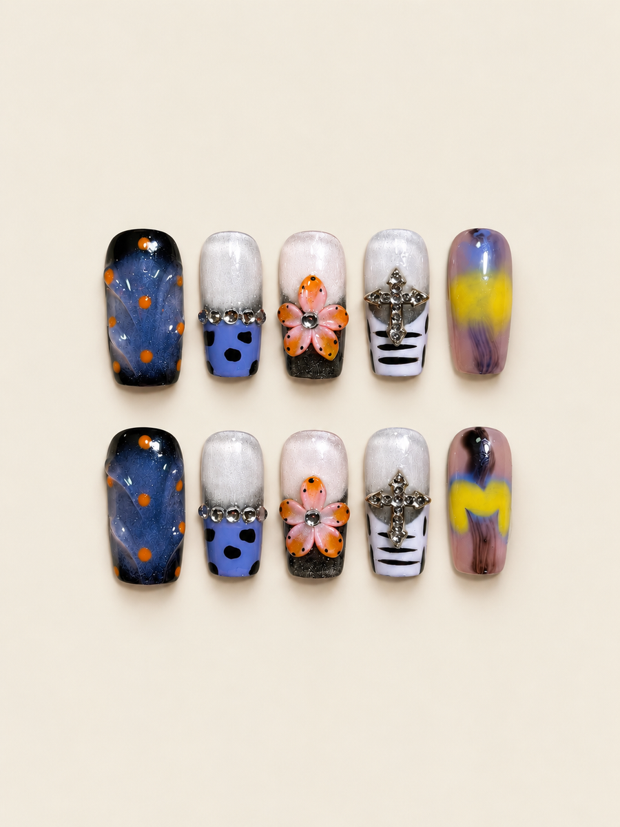 Ten glossy square press-on nails with raised peach-and-orange flowers, blue nails with orange dots, jeweled crosses, and violet-yellow swirls