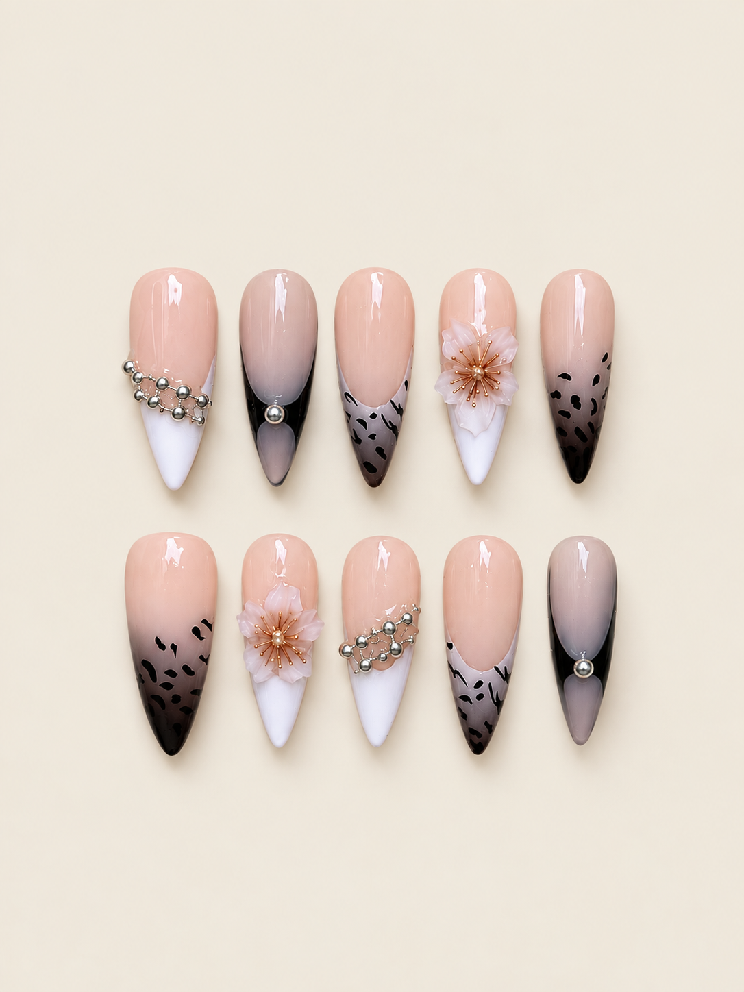 Ten pointed blush and black press-on nails with raised pink flowers, leopard spots, white tips, and silver-tone bead chains
